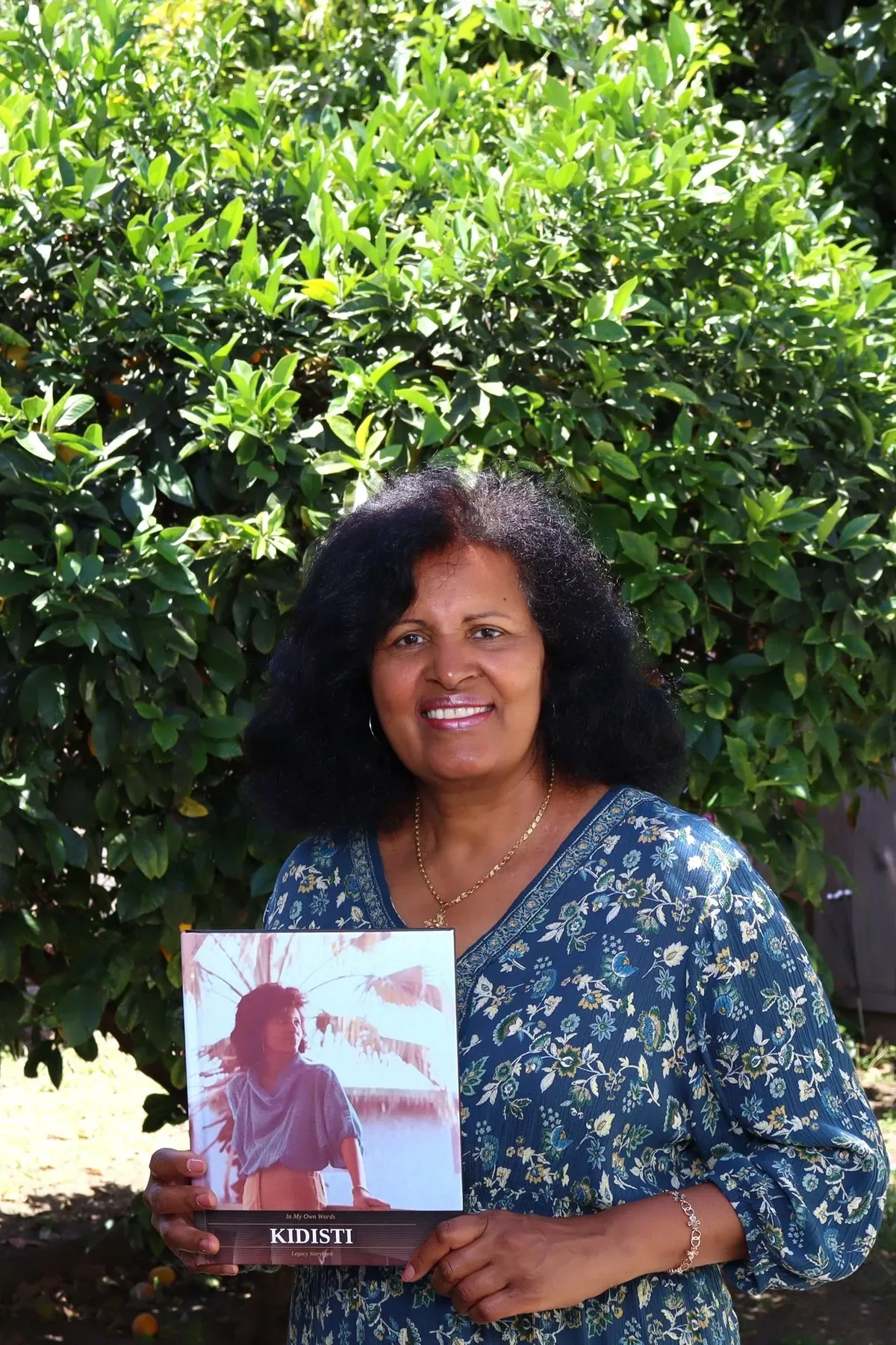 Kidisti holding her finished Legacy book outdoors in San Francisco, California.